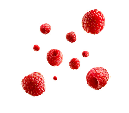 Falling ripe juicy raspberries on red background. Closeup
