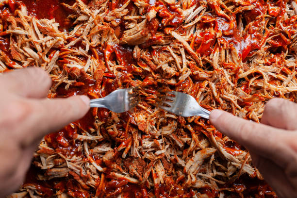 istock Pulled pork with barbecue sauce with being shredded with two forks 1338045568