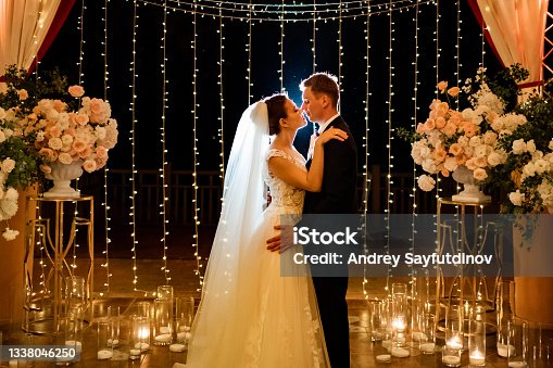 istock newlyweds at evening wedding ceremony in park among light bulbs and garlands. 1338046250