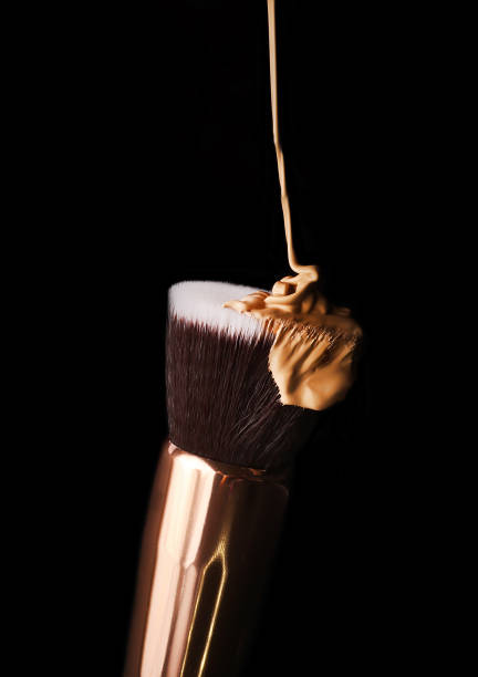 istock Makeup foundation flowing down from the brush.Slowly pouring liquid beige bb cream.Isolated on black. 1338049009