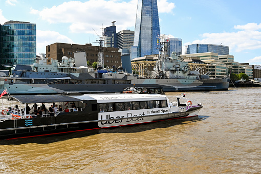 London, England - August 2021: Water taxi on the River Thames. The service is operated by Thames Clippers and sponsored by Uber