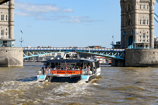 London, England - August 2021: Thames Clipper water taxi on the River Thames approaching Tower Bridge.