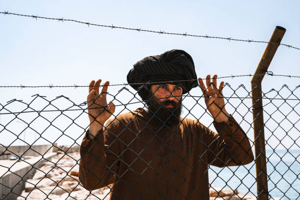 istock Refugee man standing behind the fence 1338050651