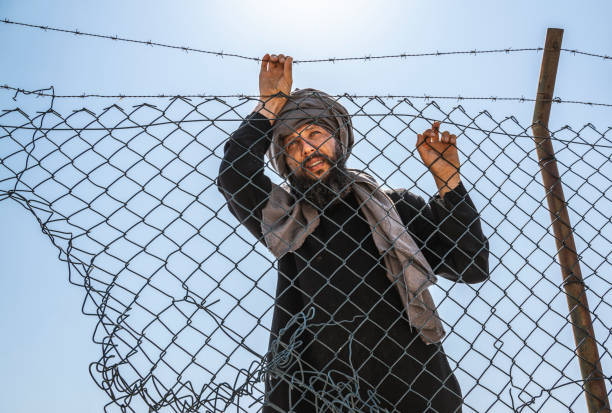 Refugee man standing behind the fence