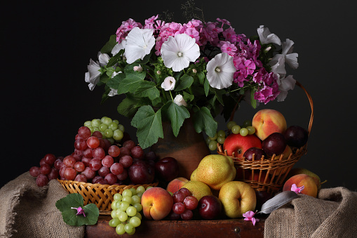 Summer still life with a bouquet of flowers, grapes, peaches, pears and plums in a retro style