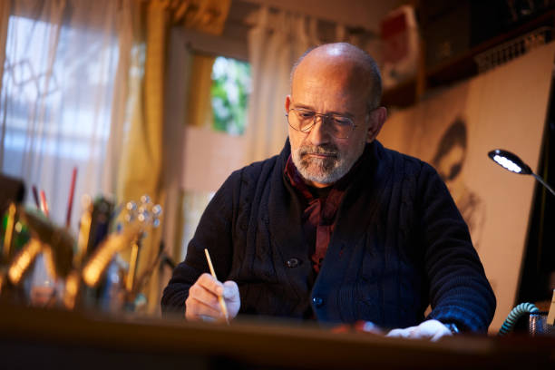 istock Artist working in studio. Middle-aged man making creative artwork, painting in watercolor with brush. 1338053612