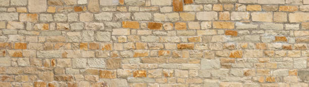 istock Old coarse panoramic stone wall in beige, ocher and brown 1338055220