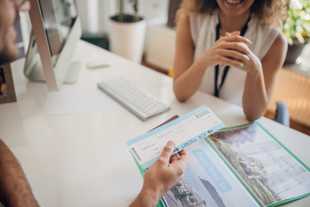 Man going on summer vacation Two people, man in modern travel agency talking with female travel agent, he is planning a vacation.. travel agency stock pictures, royalty-free photos & images
