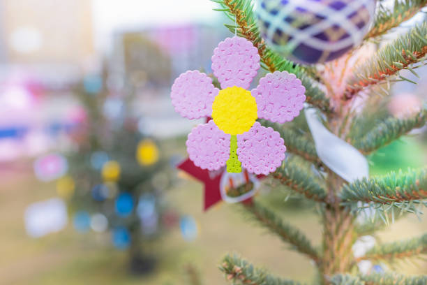 Handmade plastic pink flower decoration on Christmas tree outdoors. Creative ideas for children. Environment, recycle, reuse, upcycling and zero waste concept. Selective focus, no snow background