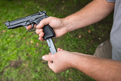 Close-up of a Man Pushing Cartridge in Pistol.