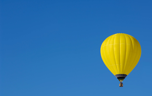 Multicolored hot air balloon on background of bright blue cloudy sky.