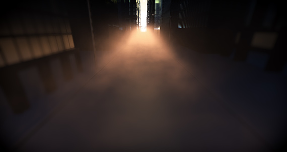 A look directly down a city street flanked with skyscrapers and lamp posts illuminated by a morning sun and dramatic fog in the distance - 3D render