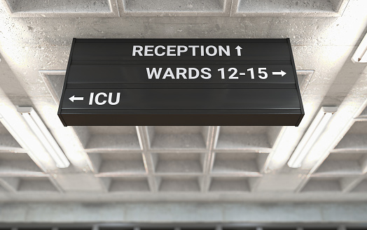 A hospital directional sign mounted on a cast concrete ceiling highlighting the way towards the ICU ward - 3D render