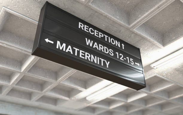 Hospital Directional Sign Maternity A hospital directional sign mounted on a cast concrete ceiling highlighting the way towards the maternity ward - 3D render maternity ward stock pictures, royalty-free photos & images