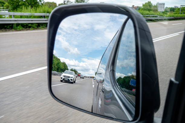 Wiesbaden, Germany - May 28, 2021: Traffic and road users on German highway A3 between Niedernhausen and Wiesbadener Kreuz on a cloudy day. Seen through the rear-view mirror. A3 is a heavily frequented German highway that connects Passau in the Southeast with the Dutch border in Germany.