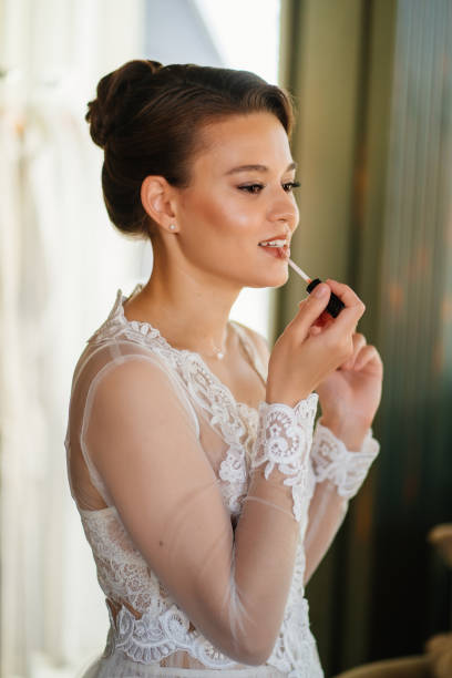 istock a beautiful bride in a lace robe paints her lips with lipstick. 1338066415