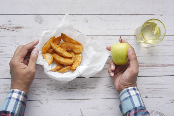 comparando cunhas de maçã e batata, comendo conceito de alimento saudável . - heathy food - fotografias e filmes do acervo