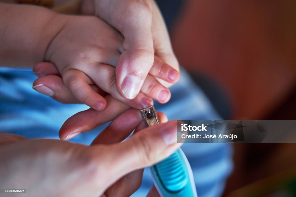 Mother cutting the baby's fingernails Adult Stock Photo