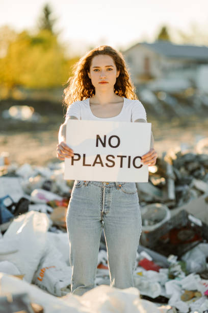 istock Young woman holding no plastic sign on trash place 1338071432