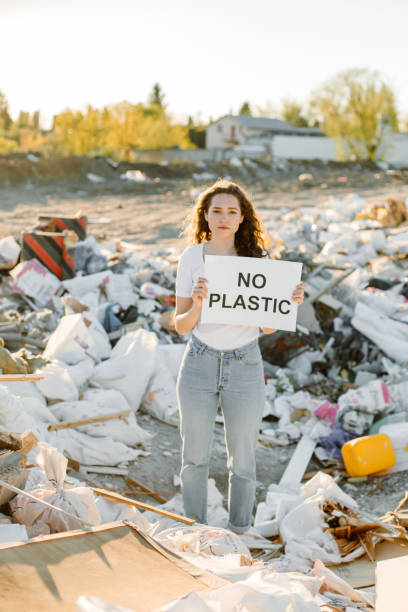 istock Young woman holding no plastic sign on trash place 1338071434