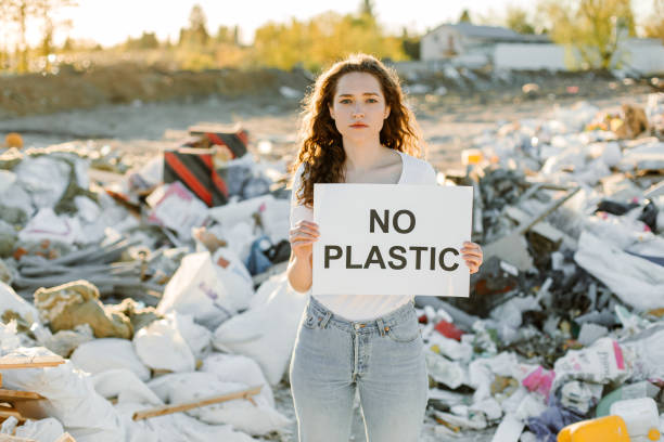 istock Young woman holding no plastic sign on trash place 1338071442