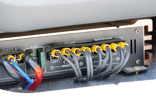 Auto electrician is connecting a wiring to car amplifier in car