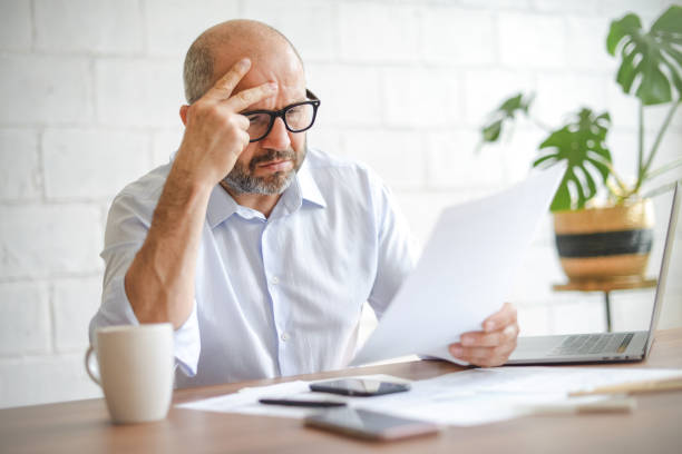 istock mature adult man working from office ( with laptop, paperwork, Negative Emotion) 1338072446