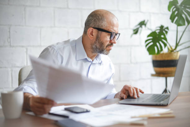 istock mature adult man working from office ( with laptop,paperwork) 1338072949