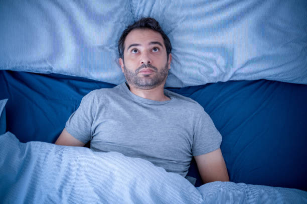 hombre ansioso tratando de dormir pero sufriendo insomnio - apnea del sueño fotografías e imágenes de stock