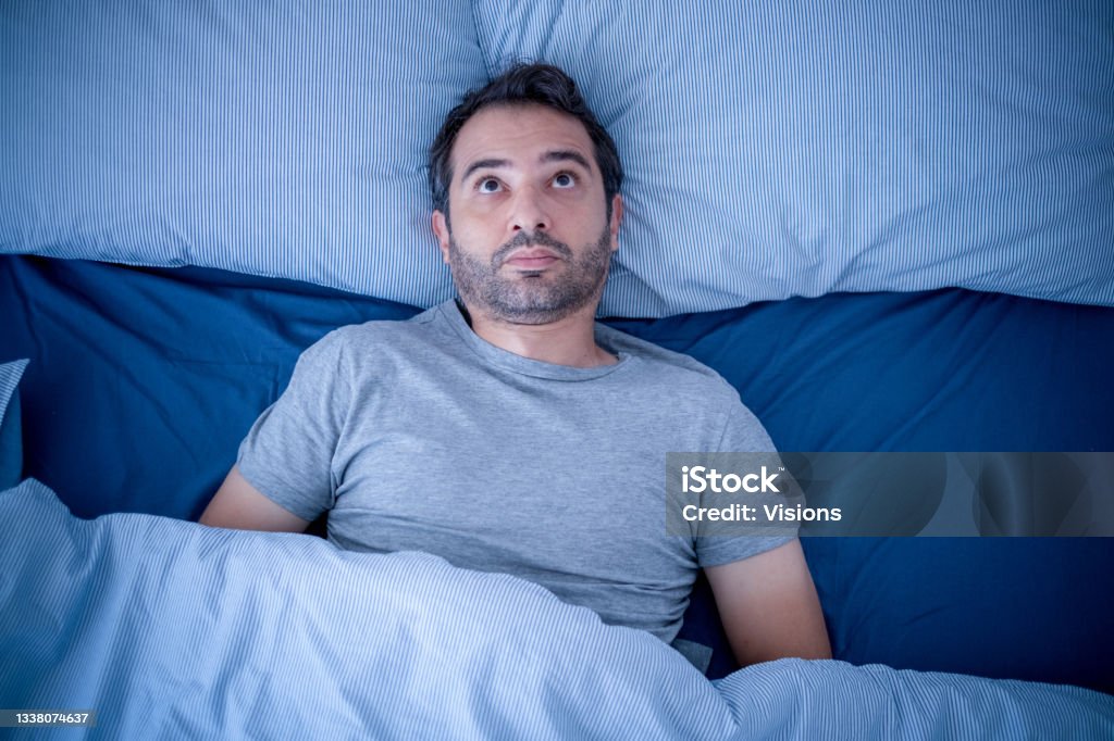 Anxious man trying to sleep but suffering insomnia Stressed man suffering from sleep problem and insomnia Insomnia Stock Photo