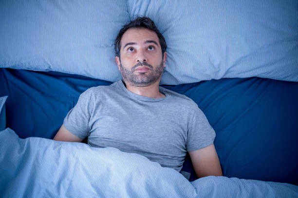 Anxious man trying to sleep but suffering insomnia Stressed man suffering from sleep problem and insomnia insomnia stock pictures, royalty-free photos & images