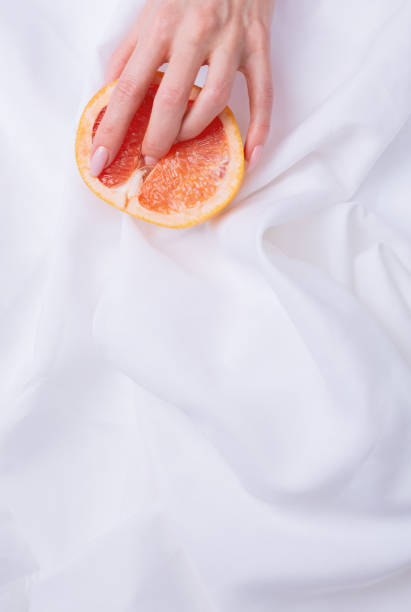 fingers on grapefruit on white background. sex concept. - orgasm imagens e fotografias de stock