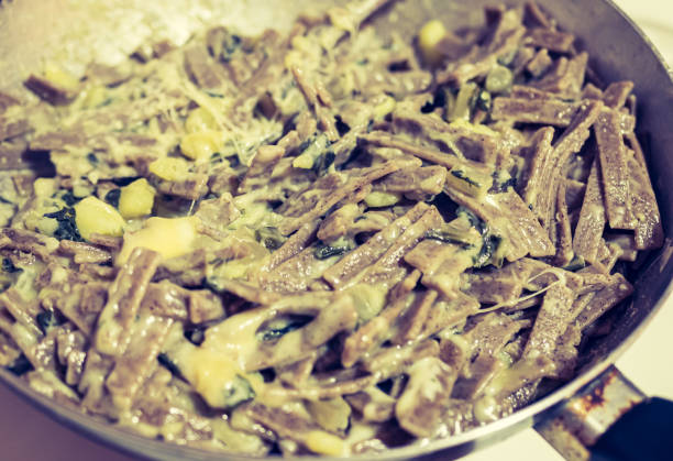 muy cerca del suculento y típico plato italiano pizzoccheri en un plato blanco sobre una mesa. plato típico de valtellina, lombardía, italia. - pizzoccheri homemade tagliatelle italy fotografías e imágenes de stock