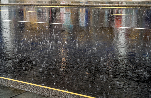 Torrential rain hitting the tarmac of a street in London.
