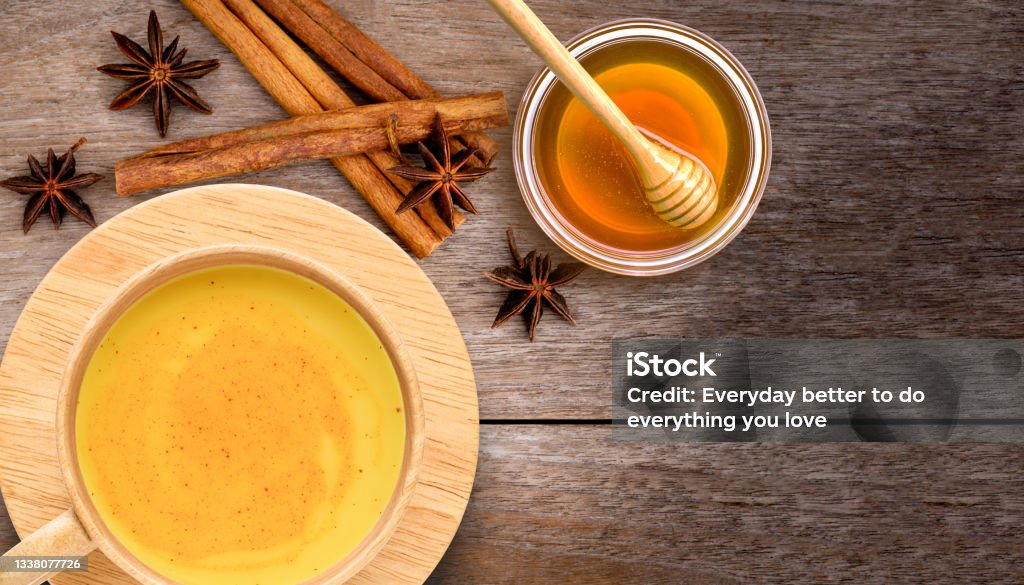 turmeric milk Golden turmeric milk (turmeric latte tea) and honey with cinnamon sticks isolated on wooden table background. Top view. Flat lay. Honey Stock Photo