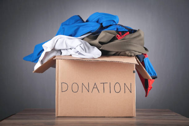 istock Donation box with clothes on the wooden table. 1338085357
