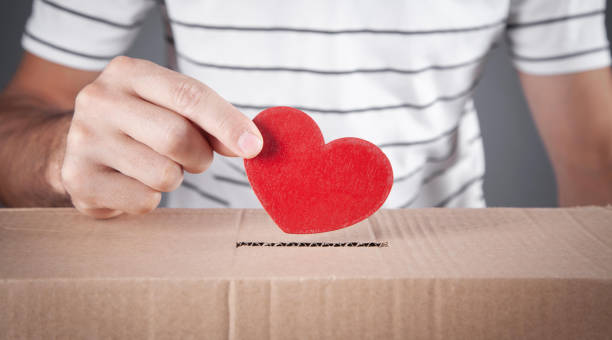 Male hand putting red heart in box. stock photo