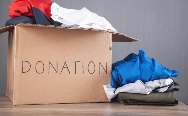 istock Donation box with clothes on the wooden table. 1338085372