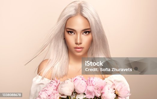 istock Black eyed beautiful blonde woman with oriental appearance is holding bouquet of rose peonies.Hairdressing and professional dyeing. 1338088678