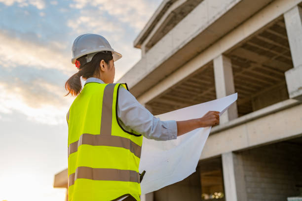 istock Young female engineer working on blueprint on construction site 1338089942