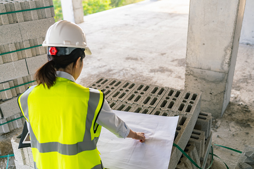 A young female engineer is working on blueprint on a construction site.