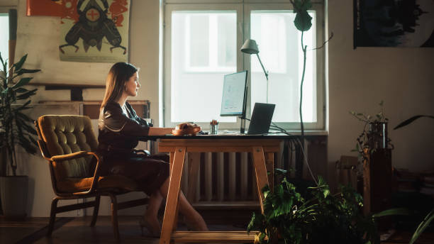 istock Young Beautiful Female Works on a Desktop Computer in Creative Agency in Authentic Loft Office. Renovated Stylish Design with House Plants, Artistic Posters and Big Windows. 1338090403