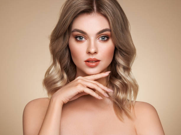 A beautiful young woman with shiny wavy blonde hair A beautiful young woman with shiny wavy blonde hair. Model with healthy skin, close up portrait. Cosmetology, beauty and spa foundation make up photos stock pictures, royalty-free photos & images