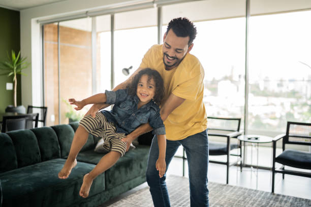 istock Man playing with his son carrying him at home 1338096429