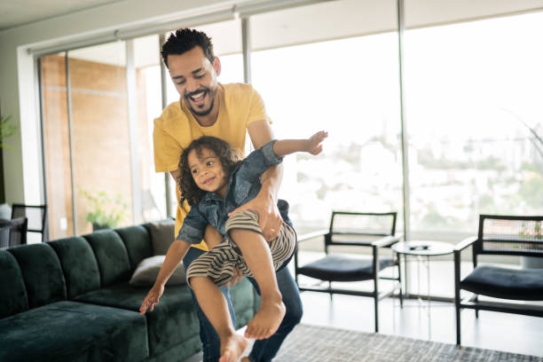 istock Man playing with his son carrying him at home 1338096433