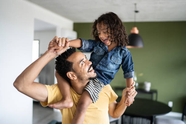 Father carrying son over shoulders at home