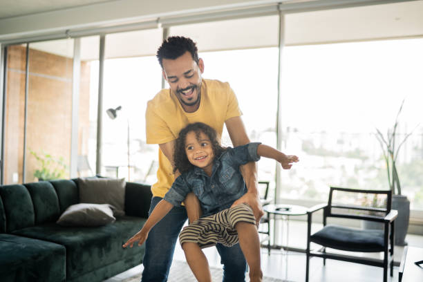 istock Man playing with his son carrying him at home 1338096517