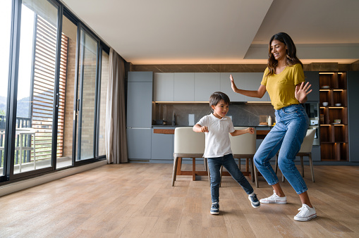 Madre feliz divirtiéndose bailando con su hijo en casa photo