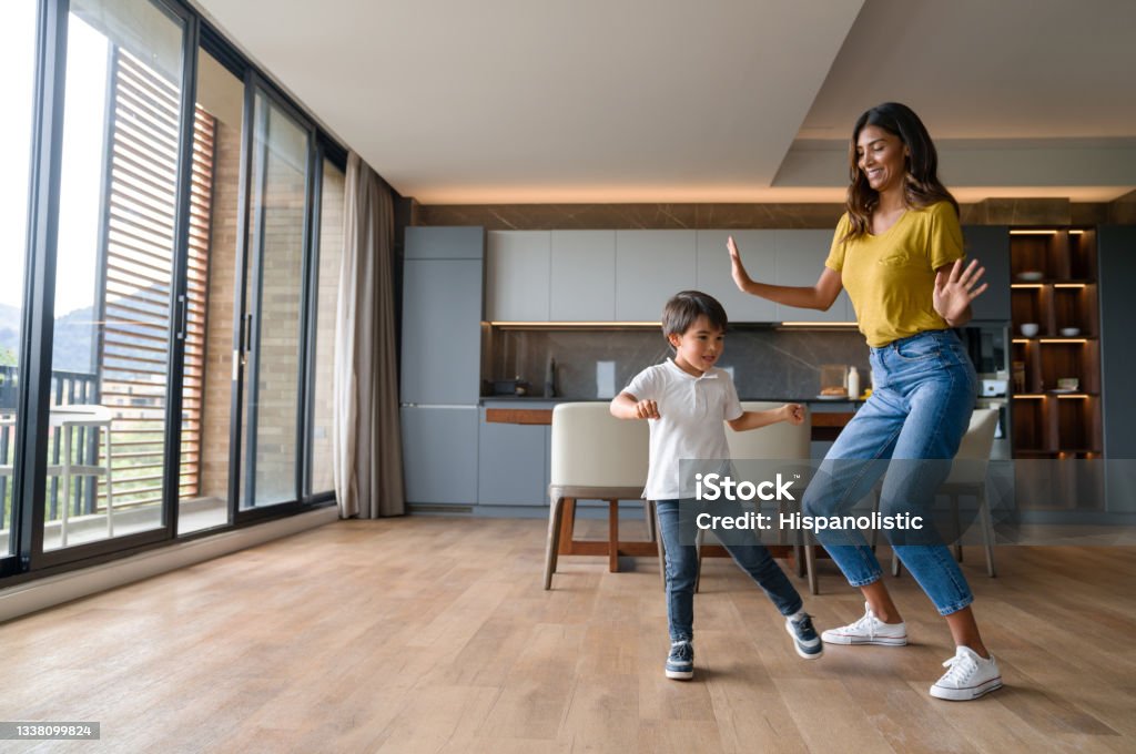 Happy mother having fun dancing with her son at home Happy Latin American mother having fun dancing with her son at home and laughing - family concepts Family Stock Photo