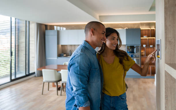 pareja que controla las características de su casa utilizando un sistema automatizado desde una tableta - termostato fotografías e imágenes de stock